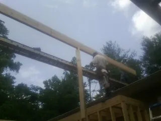 Carpenter setting a ridge beam over a new addition frame — Ice Dam Removal by Roofing Brothers in Randalia