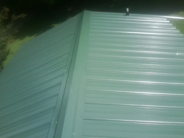 New green metal panels meeting at the ridge of a roof — Flat Roof Repair work by our crew in Randalia