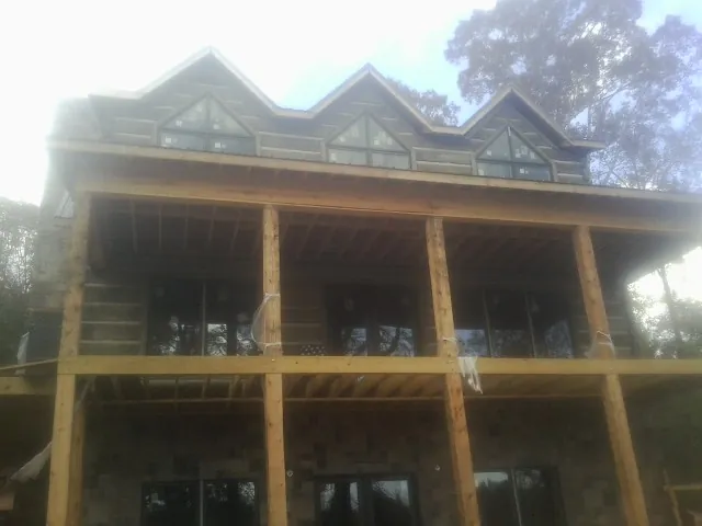 Dormers and porch framing on a large log home under construction — Roof Coating work by our crew in Randalia