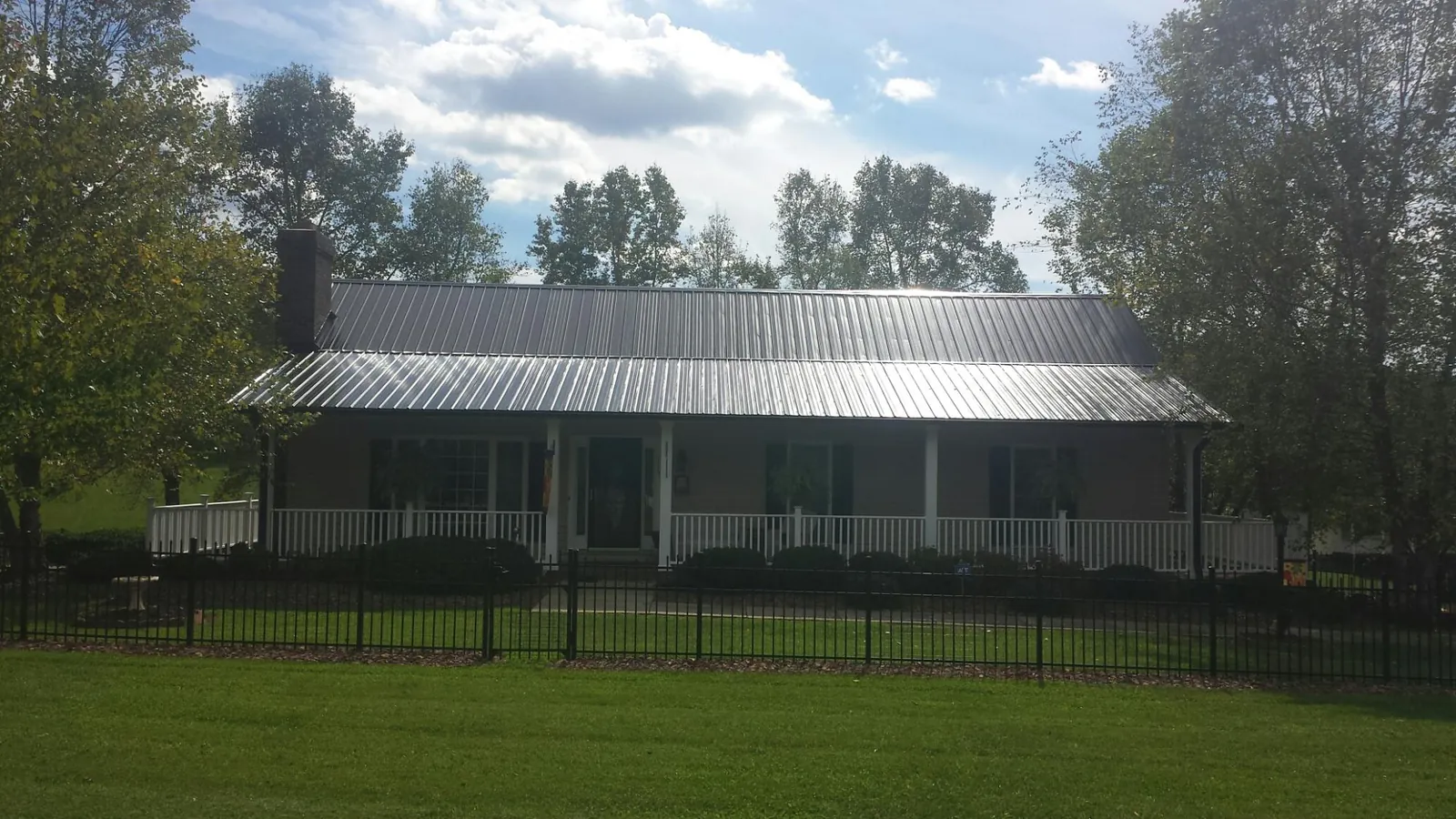 Gray metal roof on a brick ranch with a full width front porch — Gutter Guard Installation work by our crew in Randalia