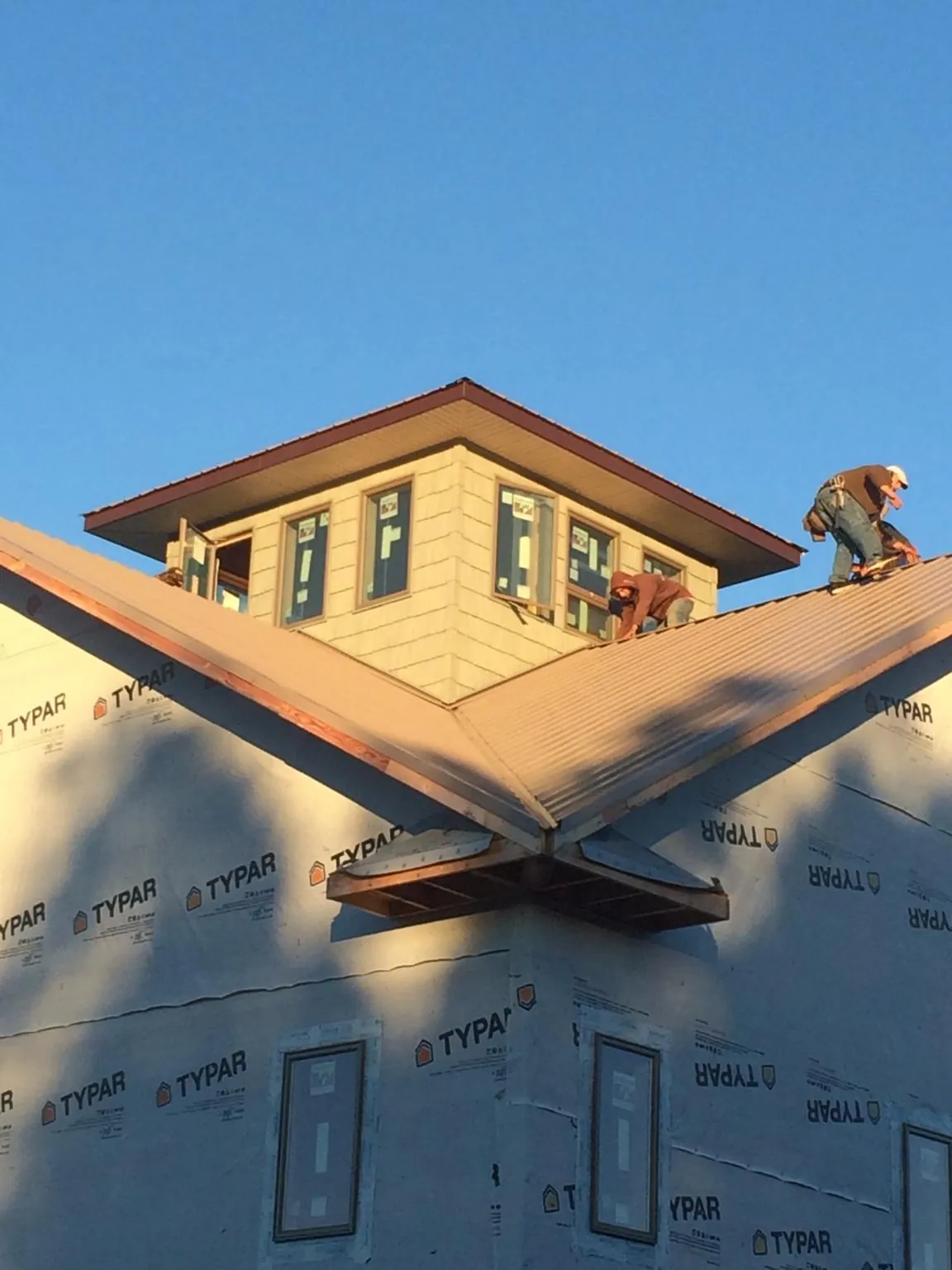 Roofers working around a rooftop cupola on a new metal roof at sunset — Roof Waterproofing in Randalia by Roofing Brothers